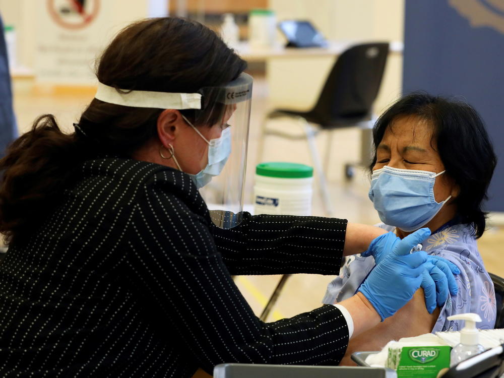 A health care worker administers a Pfizer-BioNTech COVID-19 vaccine to personal support worker Anita Quidangen at The Michener Institute, in Toronto, Canada, on Monday. Quidangen was one of the first people in Canada to receive the shot.