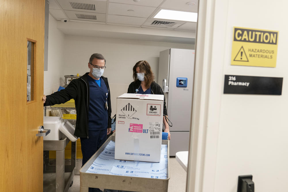Pharmacists Richard Emery and Karen Nolan wheel a box containing the Pfizer-BioNTech COVID-19 vaccine next to a storage freezer as it arrives at Rhode Island Hospital in Providence, R.I, on Monday.