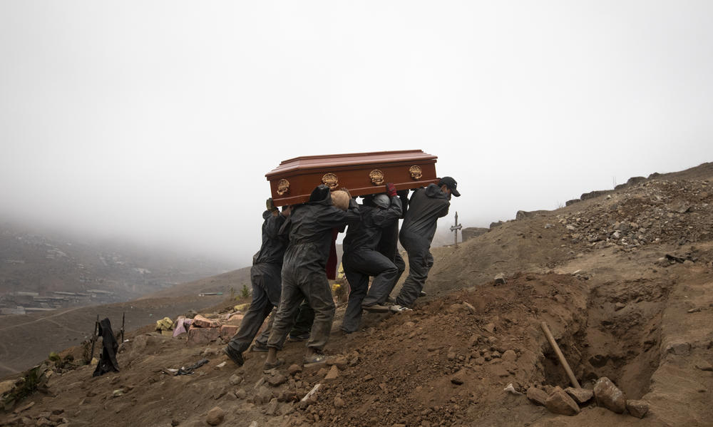 Cemetery workers in Lima, Peru, carry the coffin of a person who died from the coronavirus.