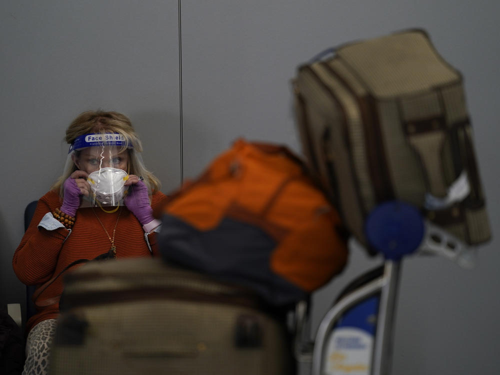 A traveler adjusts her mask while waiting to check in for her flight at the Los Angeles International Airport on Nov. 23.