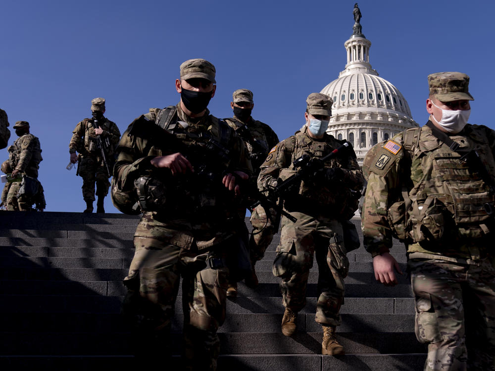Members of the National Guard walk past the Capitol in Washington on Thursday. By next week, they will be joined by thousands of others.