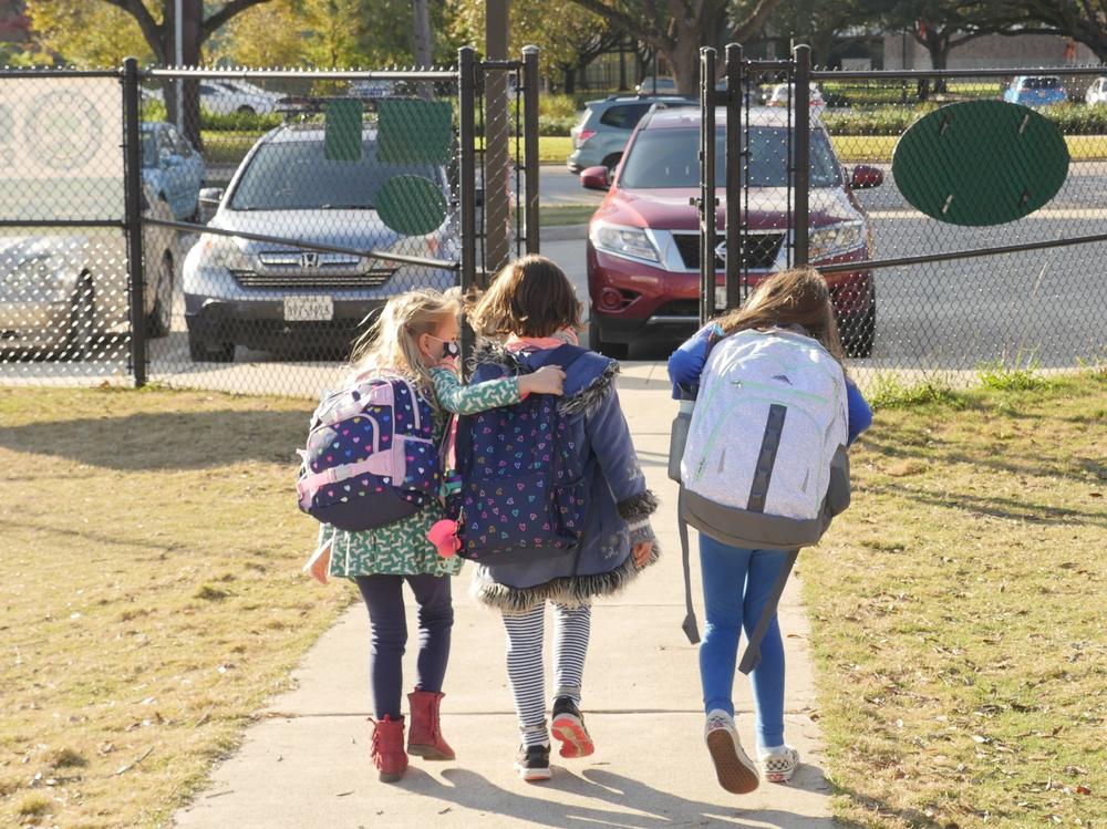 School children wearing facemasks walk outside Condit Elementary School near Houston in December. The U.S. Department of Education announced Friday that it will begin collecting data on the status of in-person learning during the pandemic.