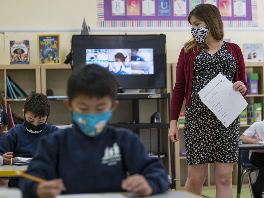 A teacher wearing a protective mask walks around the classroom during a lesson at an elementary school in San Francisco in October 2020.