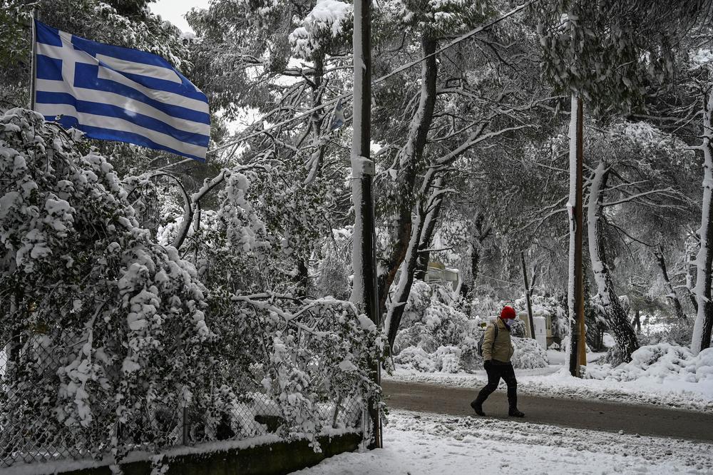 A man walks on a snow-covered street during snowfall in a northern suburb of Athens.