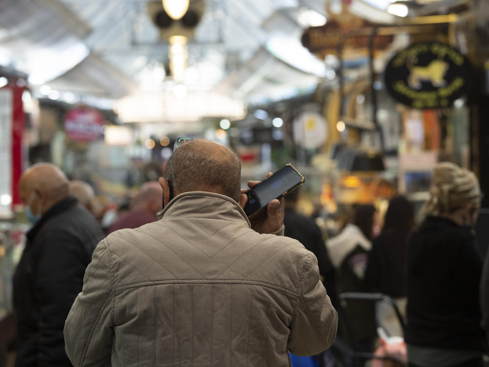 A man speaks on his mobile phone in the Mahane Yehuda market in Jerusalem in December. In the early days of the pandemic, Israel began using a mass surveillance tool on its own people, tracking civilians' mobile phones to halt the spread of the coronavirus.