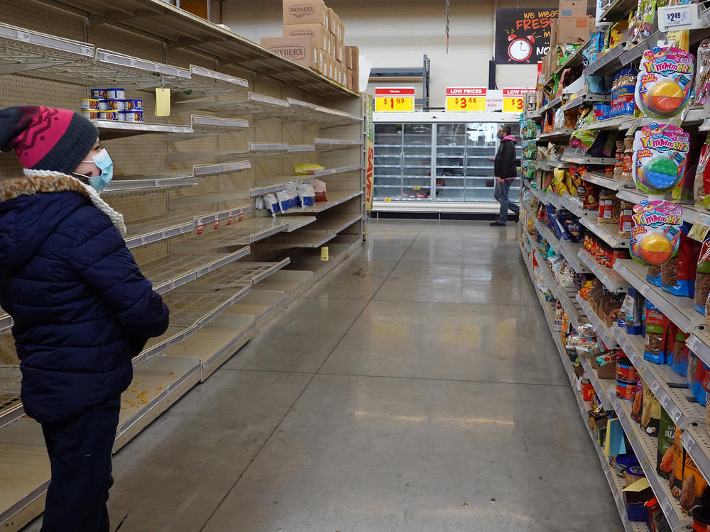A shopper walks past a mostly bare shelf as people stock up on necessities at the H-E-B grocery store in Austin, Texas, on Feb. 18. A devastating winter storm that hit the middle of the country last month helped send retail sales tumbling.