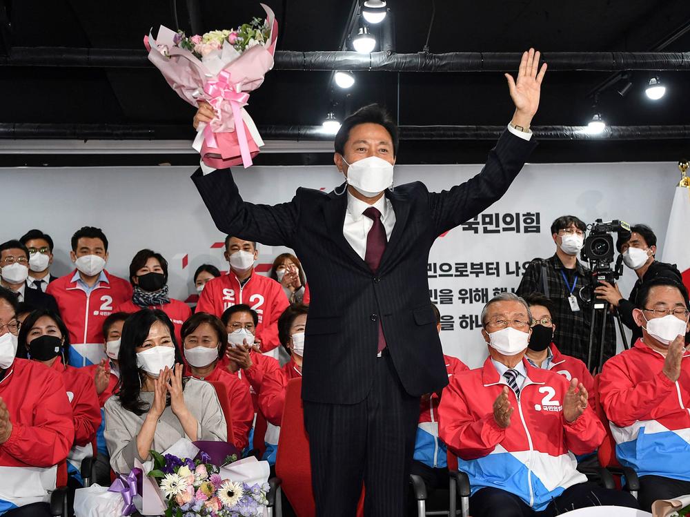 Oh Se-hoon (center), the mayoral candidate of the main opposition People Power Party, holds flowers as he celebrates with party members after exit polls showed he would win.