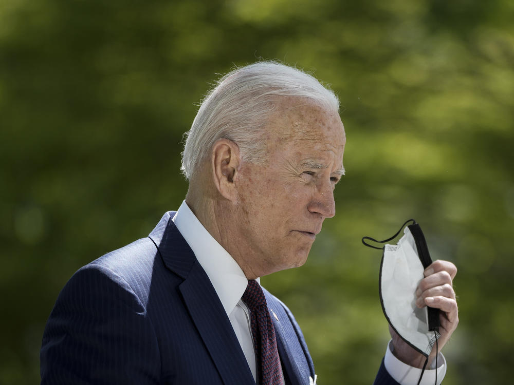 President Biden removes his mask before speaking about the pandemic Tuesday afternoon outside the White House.