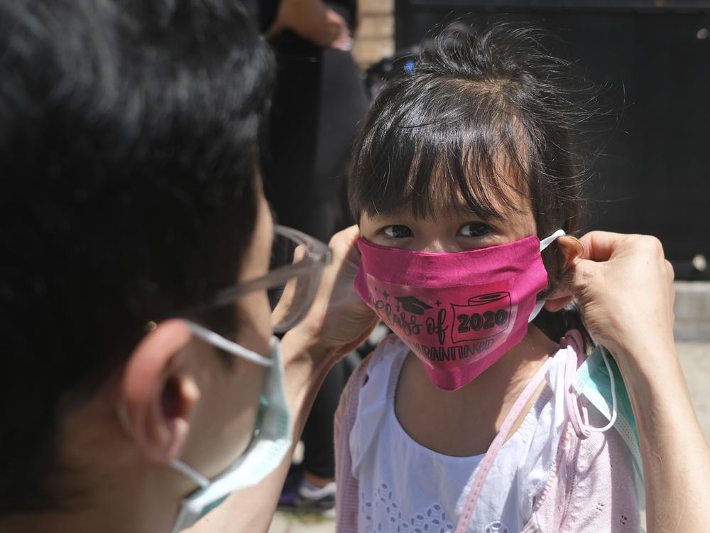 A girl in Jersey City wears a mask at her Pre-K graduation ceremony almost a year ago. Now schools are deciding how looser CDC guidelines on masks affect education.