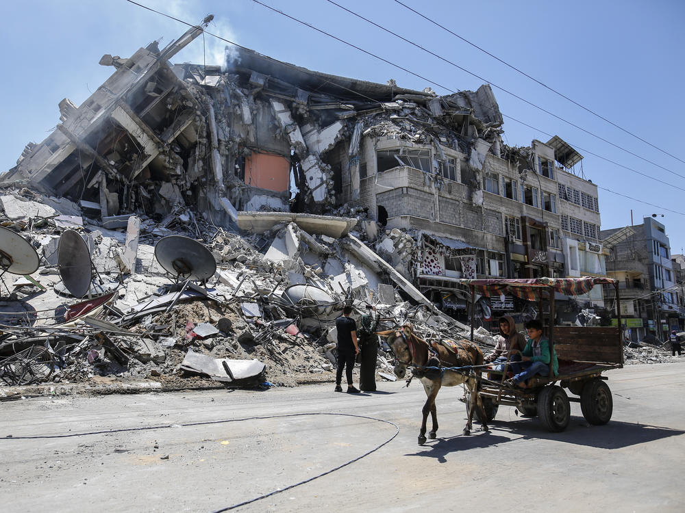 Palestinians walk past the debris of the Al-Sharouk tower in Gaza City, which collapsed after being hit by an Israeli air strike.