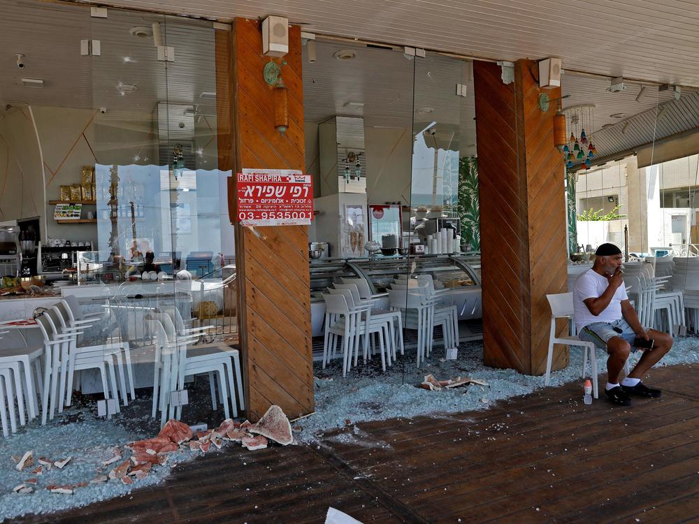 An Israeli man sits at a restaurant Thursday that was attacked the previous night in Israel's coastal city of Bat Yam. Israel faces an escalating conflict on two fronts, scrambling to quell riots between Palestinian and Jewish citizens on its own streets after days of exchanging deadly fire with militants in Gaza.