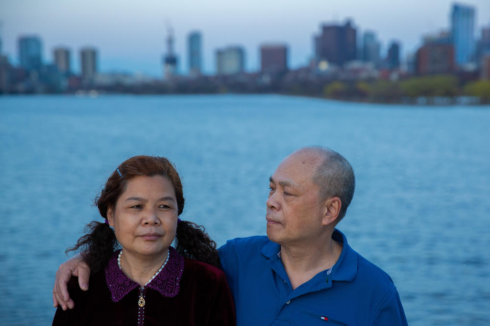 Liang Runling, 56, sits with her husband, Chen Yuning, along the Charles River in Boston.