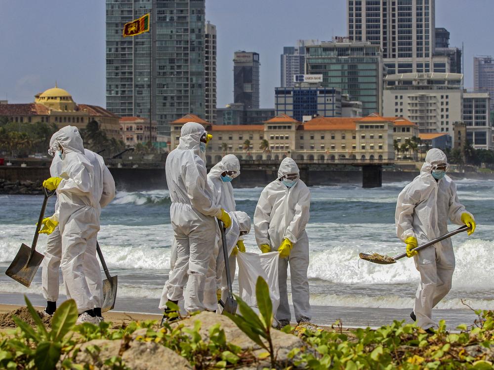Members of the Sri Lankan navy remove debris washed ashore from the X-Press Pearl, which has been burning offshore of Colombo, Sri Lanka's capital, for nearly two weeks.