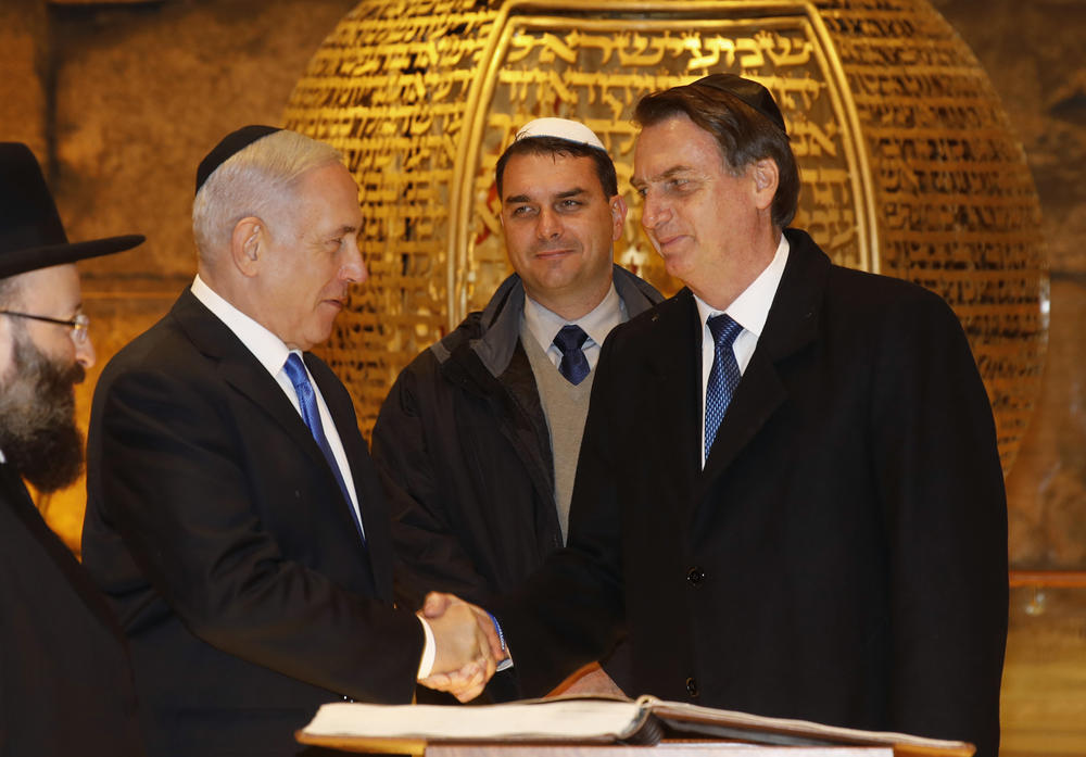 Brazilian President Jair Bolsonaro and Israeli Prime Minister Benjamin Netanyahu shake hands near the Rabbi of the Western Wall Shmuel Rabinovitch, left, and Bolsonaro's son Flavio, center, during a visit to a synagogue inside the Western Wall Tunnels in Jerusalem's Old City in April 2019.