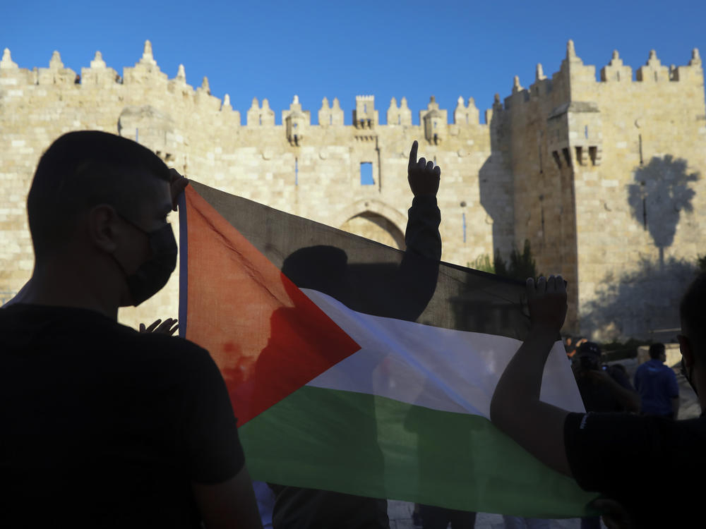 Demonstrators wave the Palestinian flag during a protest in Damascus Gate, just outside Jerusalem's Old City on June 19. Palestinians and Jewish settlers hurled stones, chairs and fireworks at each other in a tense Jerusalem neighborhood, where settler groups are trying to evict several Palestinian families, officials said Tuesday.