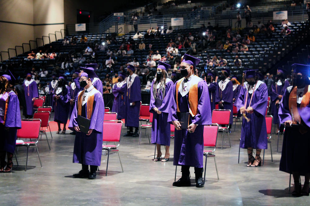 Masked students from Edna Karr High School in New Orleans stand at their graduation ceremony. The school split the graduating class in half to allow for social distancing, then held identical indoor ceremonies back to back.