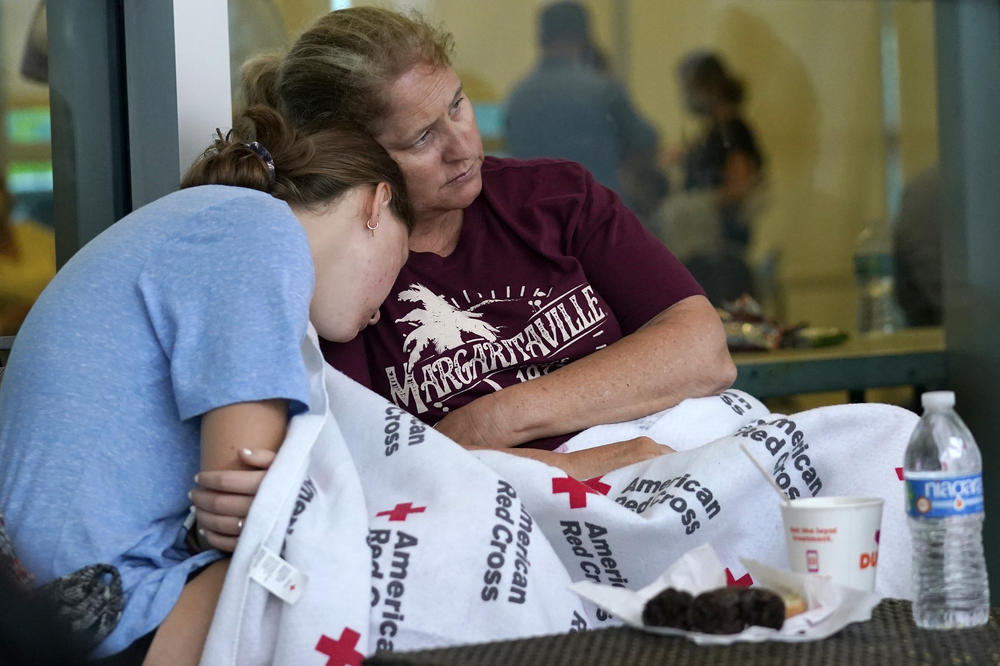 Jennifer Carr, right, sits with her daughter as they wait for news at a family reunification center near the partially collapsed building. Carr and her family were evacuated from a nearby building.