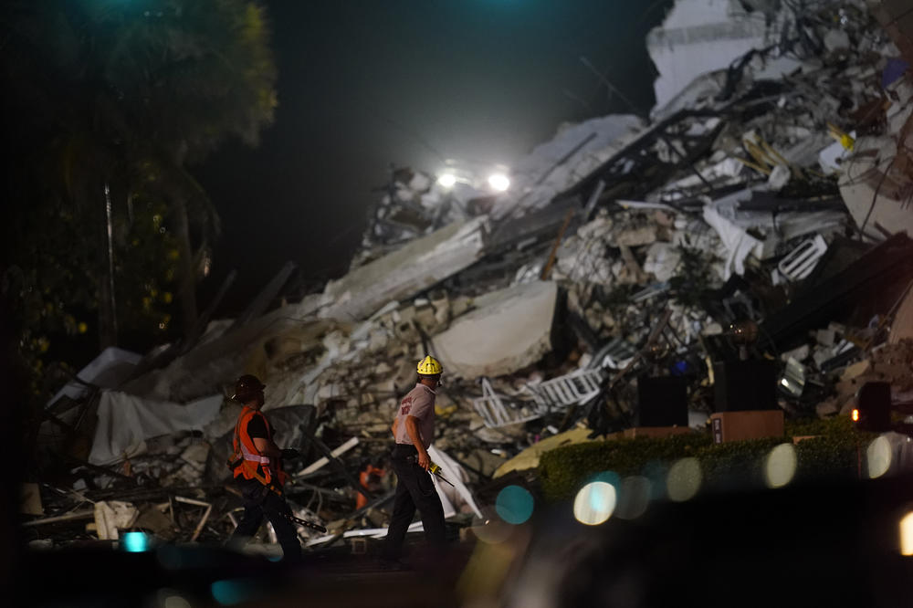 Rescue workers walk beside the rubble as rescue efforts continued on Thursday night.