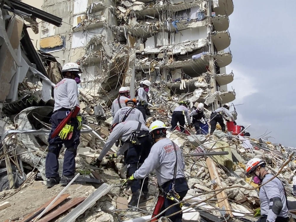 In this photo provided by Miami-Dade Fire Rescue, search-and-rescue personnel search for survivors through the rubble at the Champlain Towers South Condo in Surfside, Fla., on Friday.