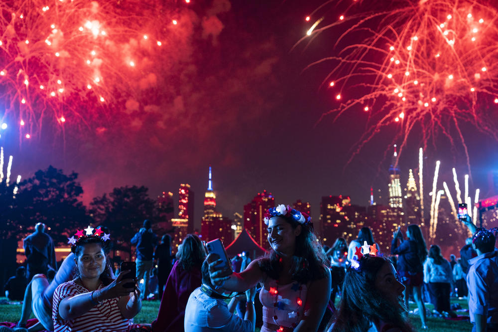 Spectators watch as fireworks are launched over the East River and the Empire State Building during the Macy's 4th of July Fireworks show, Sunday, in the Queens borough of New York City.