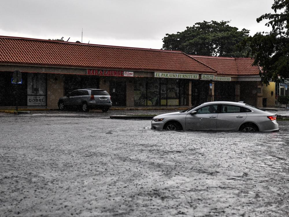 A woman drives through floodwater during heavy rainfall in Miami. A new study predicts that high tide flooding in coastal areas could increase in frequency because of climate change and the lunar cycle in the mid-2030s.