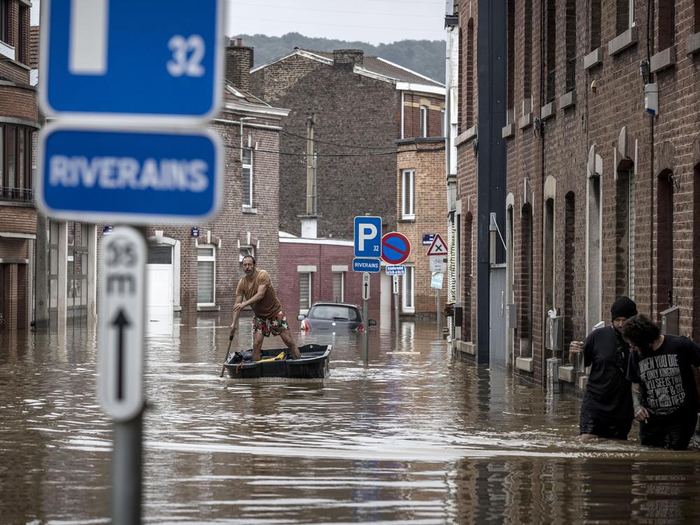A man rows a boat down a residential street after flooding in Liège, Belgium, on Friday.