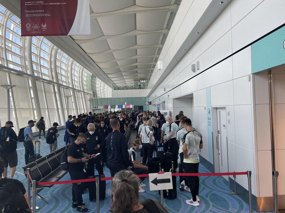 Long lines of people arriving for the Olympics wait to pass through an array of safety protocols at Haneda Airport in Tokyo.