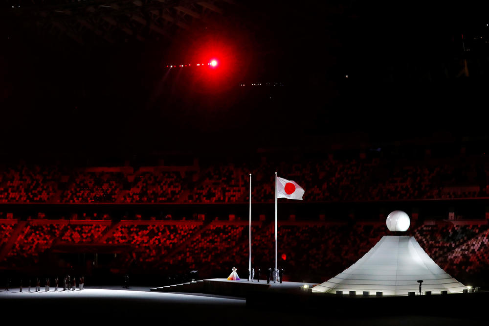 The Olympic cauldron is seen as the Japanese flag is raised during the national anthem.