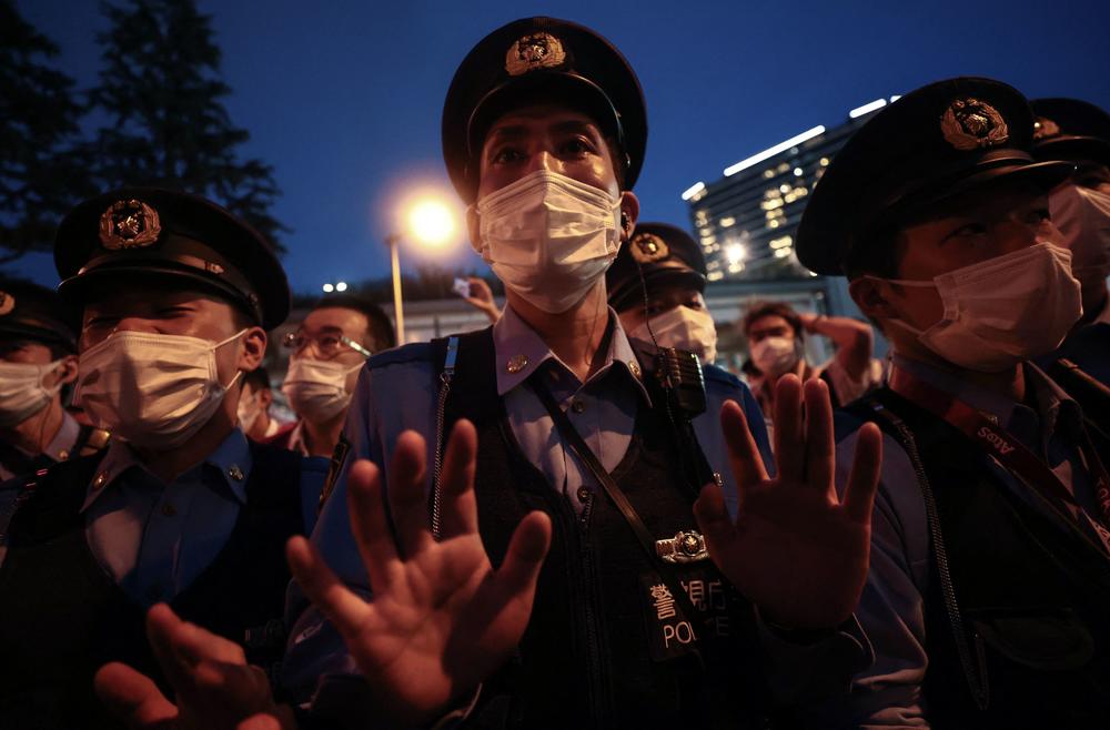 A police officer gestures toward a small group (not seen) protesting against the Tokyo Games on Friday.