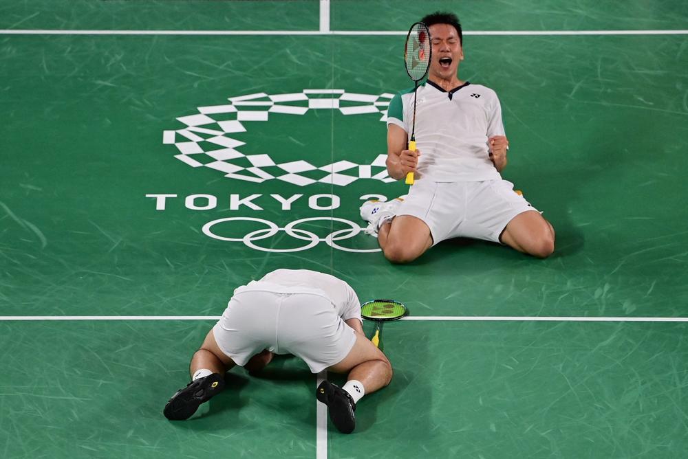 Taiwan's Wang Chi-lin, bottom, and Taiwan's Lee Yang react after winning their men's doubles badminton group stage match against Indonesia's Marcus Fernaldi Gideon and Indonesia's Kevin Sanjaya Sukamuljo on July 27, 2021.