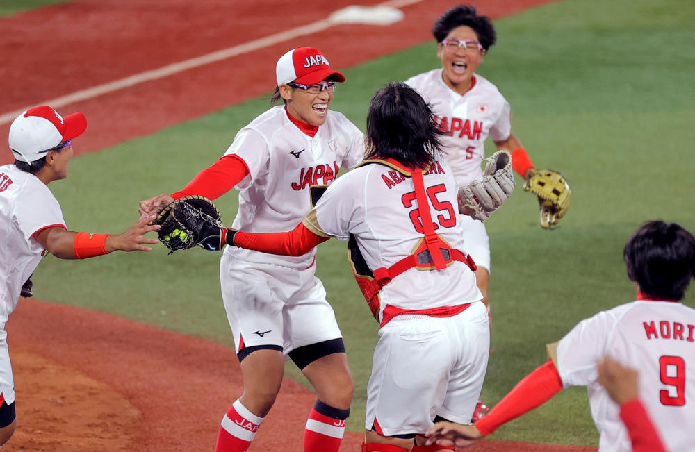 Japan's pitcher Yukiko Ueno, 2nd left, and catcher Haruka Agatsuma, center, celebrate their gold medal victory as other teammates run to join on July 27, 2021.