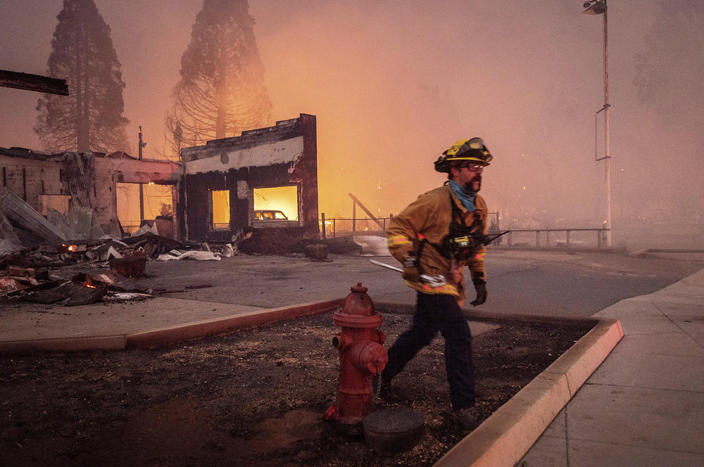A firefighter battles the Dixie Fire as it tears through the Greenville community.