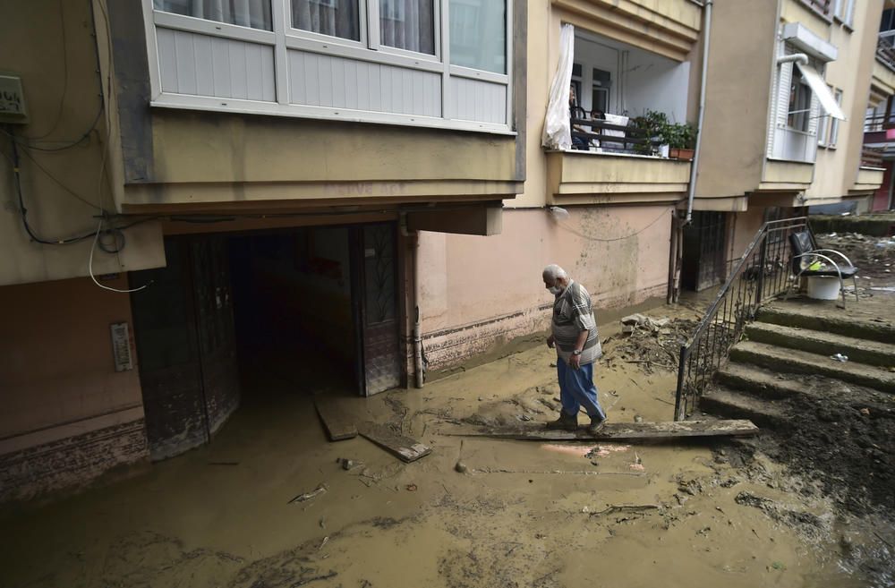 A man tries to reach his mud-filled home after floods and mudslides killed about three dozens of people, in Bozkurt town of Kastamonu province, Turkey, Friday, Aug. 13, 2021. An opposition politician said more than 300 people may be unaccounted-for.