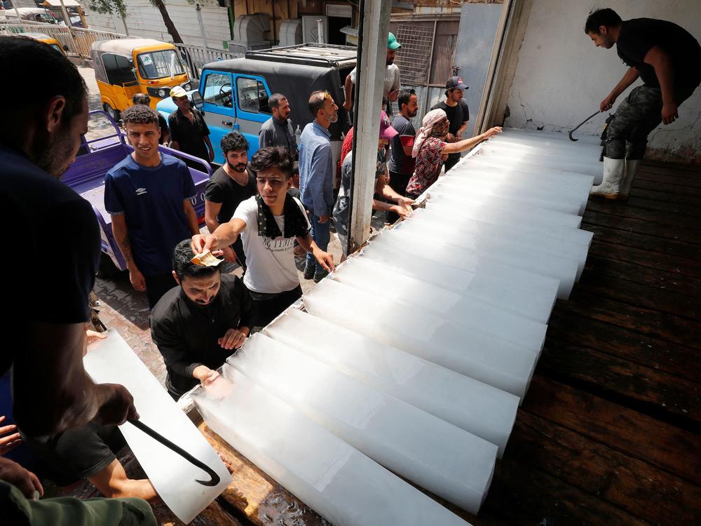 Iraqis buy ice blocks at a factory in Sadr City, east of the capital, Baghdad, on July 2 amid power outages and soaring temperatures.