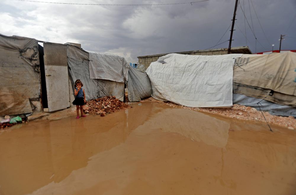 A young Syrian girl stands by a water puddle caused by torrential seasonal rain flooding the 