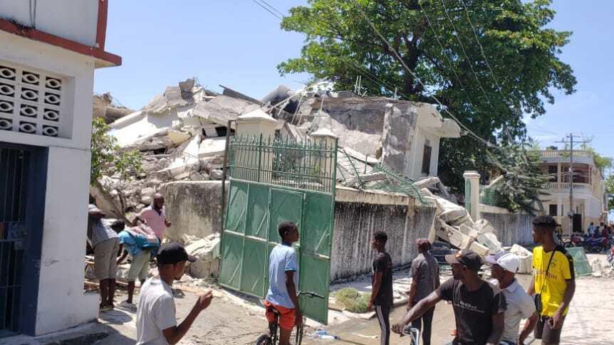 People stand outside the residence of the Catholic bishop after it was damaged by an earthquake in Les Cayes on Saturday.