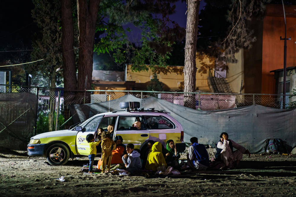 <strong>Sat., Aug. 14:</strong> A small group of Afghans eat their meal quietly outside of their vehicle which they also use to live in temporarily, in the corner of a parking area near the makeshift camps at Shahr-e-Naw Park in Kabul.