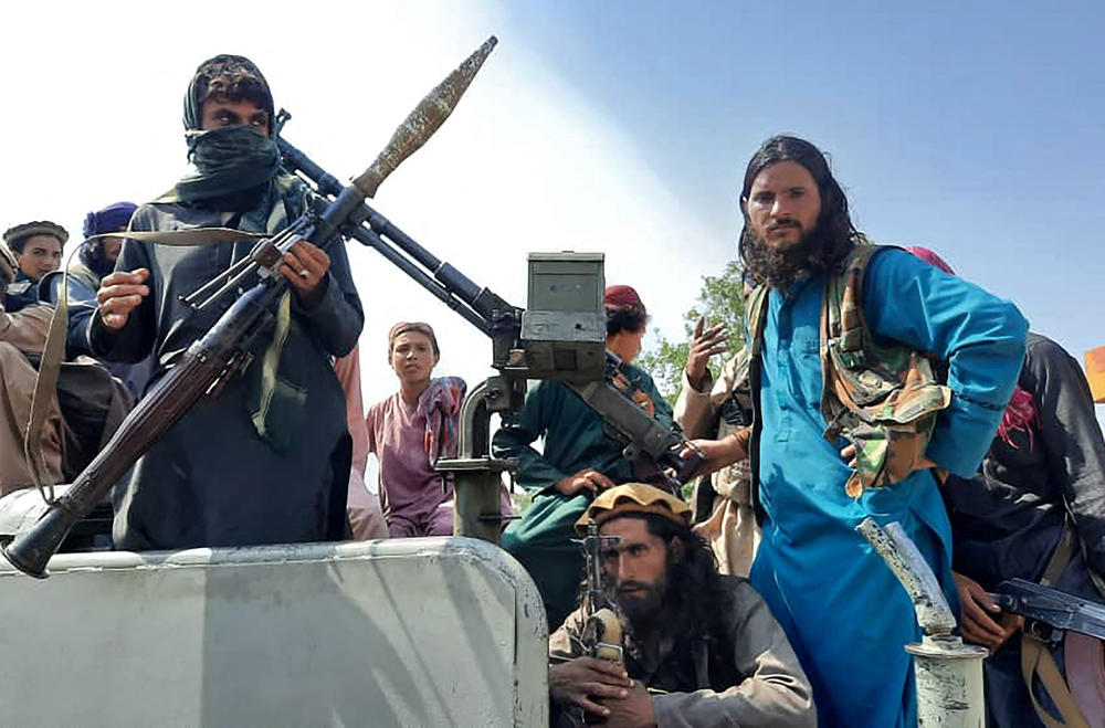 <strong>Sun., Aug. 15:</strong> Taliban fighters sit over a vehicle on a street in Laghman province.