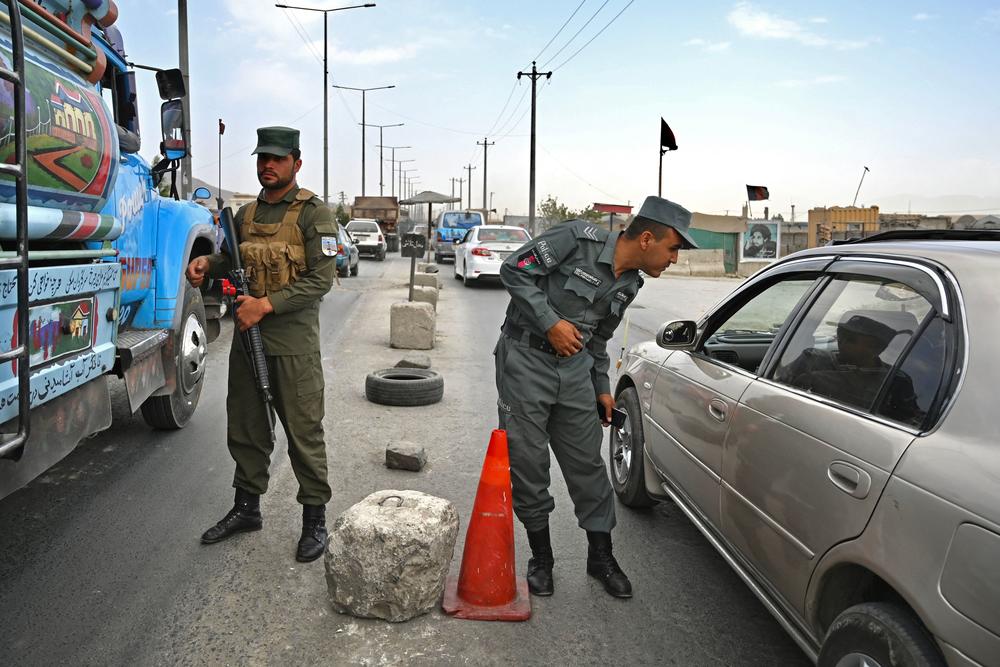 <strong>Sat., Aug. 14:</strong> Afghan policemen stand guard at a checkpoint along the road in Kabul.