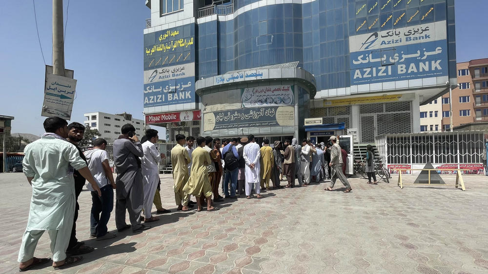 People line up outside Azizi Bank to take out cash as the Taliban close in on the capital Kabul on Sunday.