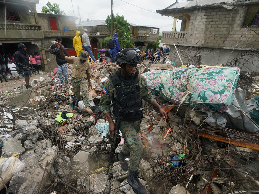 A soldier walks over earthquake rubble on Tuesday, the morning after Tropical Storm Grace swept over Les Cayes, Haiti, three days after the 7.2 magnitude quake.