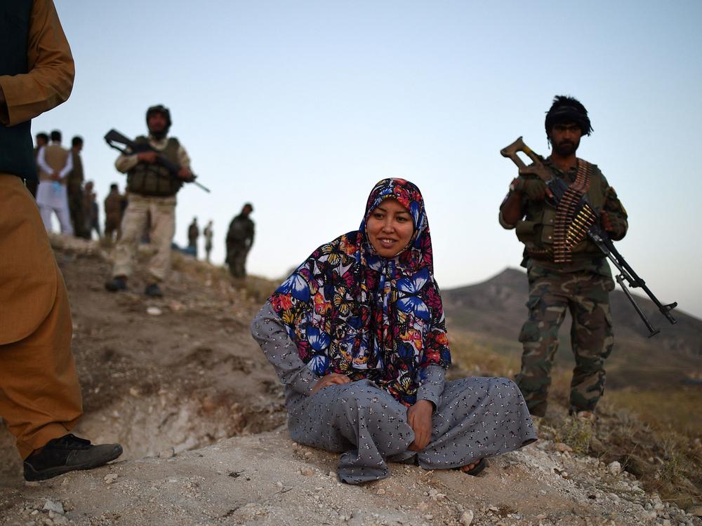 Salima Mazari, a district governor in Afghanistan, looks on from a hill on July 14 while accompanied by security personnel near the front lines against the Taliban in the Charkint district in Balkh province.