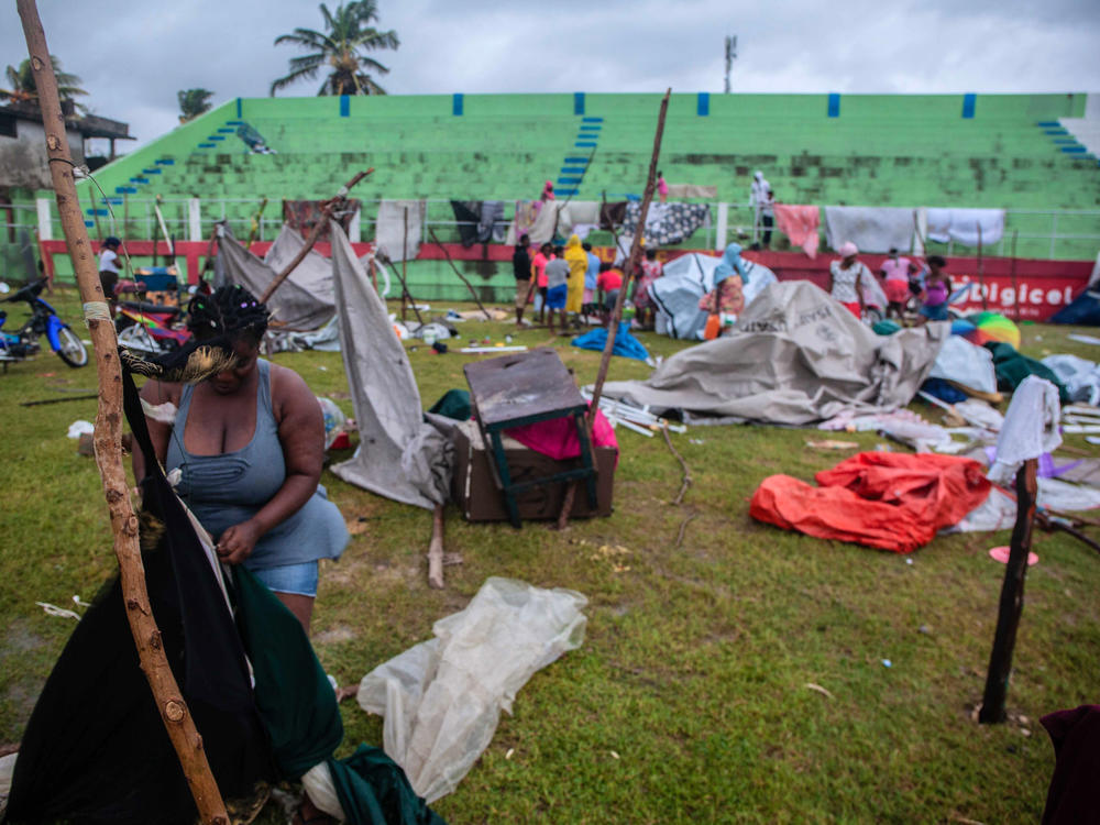 In the aftermath of Tropical Storm Grace, a woman works on a shelter at an improvised camp at Parc Lande de Gabion stadium.