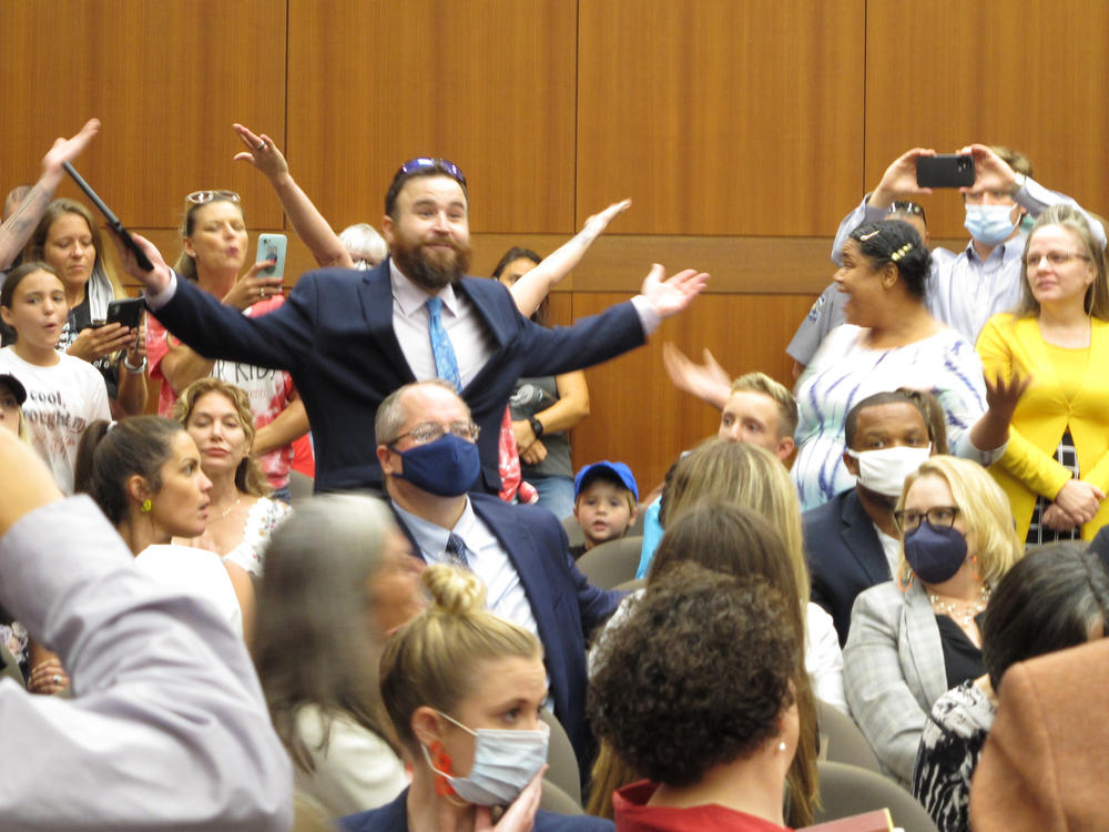 Angry, largely unmasked people objecting to Louisiana Gov. John Bel Edwards' mask mandate for schools shout in opposition to wearing a face covering at the Board of Elementary and Secondary Education meeting on Wednesday in Baton Rouge, La.