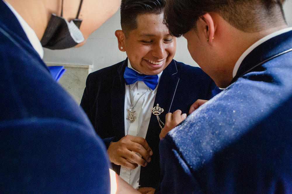 Juan Tlatelpa receives help with placing an adornment oh his suit.