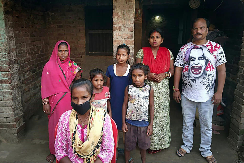 Jyoti Kumari (center, foreground, in mask) and family members stand in front of their house in Sirhulli, a village in eastern India.
