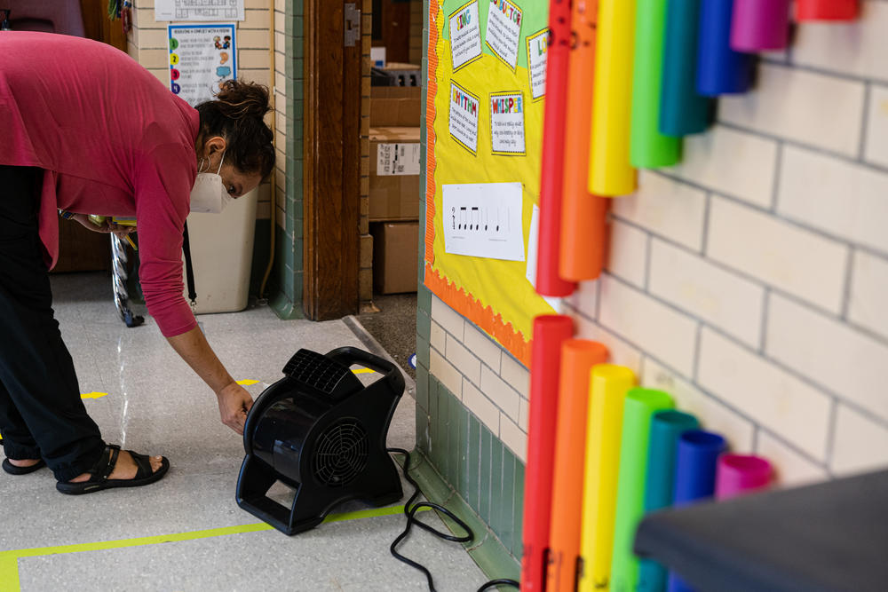 Quesada turns on a fan outside her classroom door. She spends most of her time before class on COVID-19 precautions. She has spent nearly $600 of her own money on air purifiers and fans to improve the ventilation in her classroom.