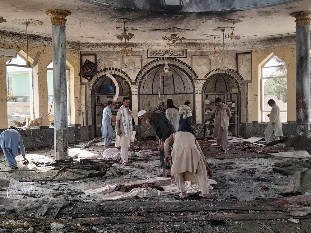 People sift through the damage inside of a mosque following a bombing in Kunduz province northern Afghanistan on Friday.