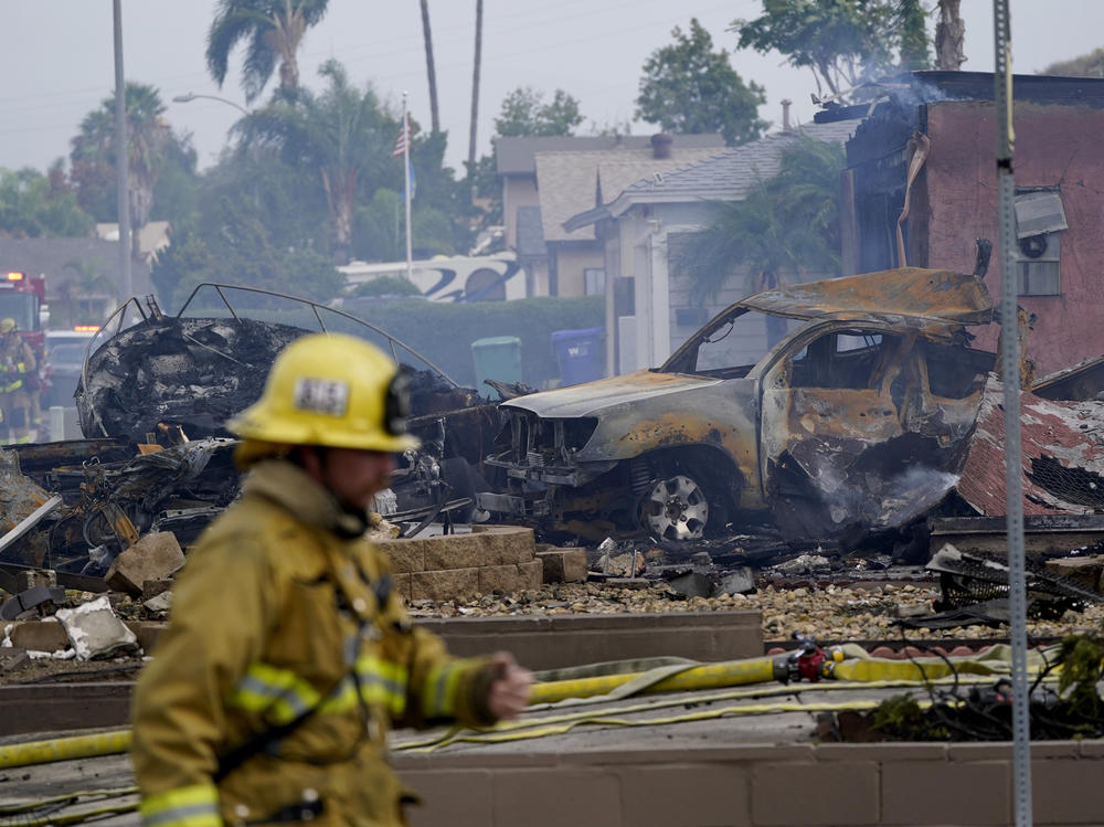 Fire crews work the scene of a small plane crash on Monday in Santee, Calif. At least two people were killed and two others were injured when the plane crashed into the suburban neighborhood, setting two homes ablaze.