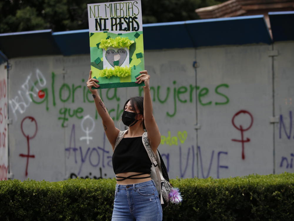 A woman holds a placard that reads in Spanish 